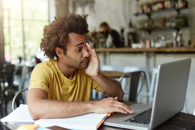 Confused and stressed business owner on laptop in public setting